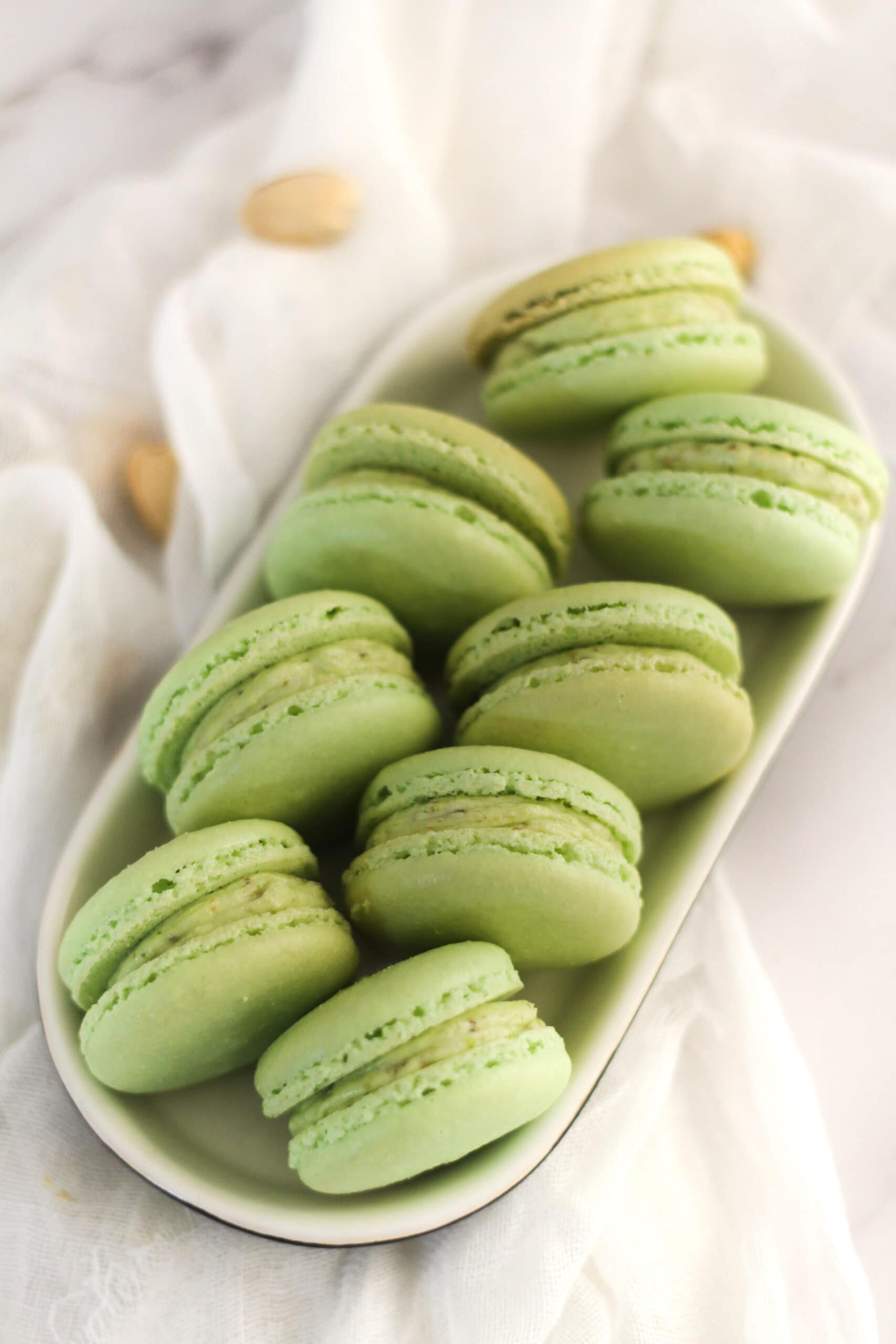 Pistachio macarons resting in oval plate