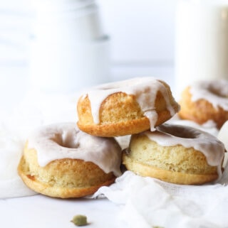 cardamom donuts stacked in front of a bottle of milk