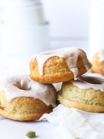 cardamom donuts stacked in front of a bottle of milk