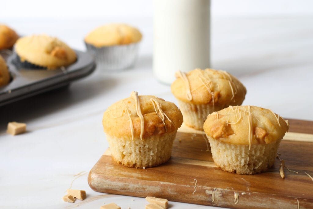 Caramilk muffins on wooden board with melted caramilk drizzled on top