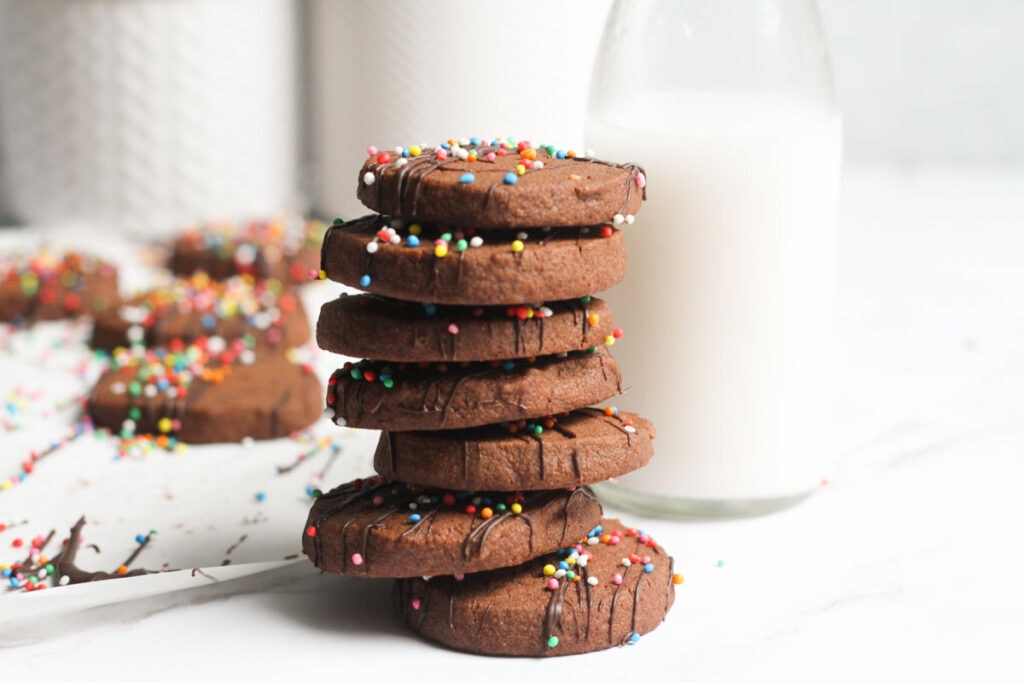 Stacked slice and bake chocolate shortbread cookies with jar of milk.