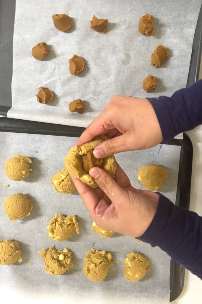 Placing biscoff ball into cookie dough.