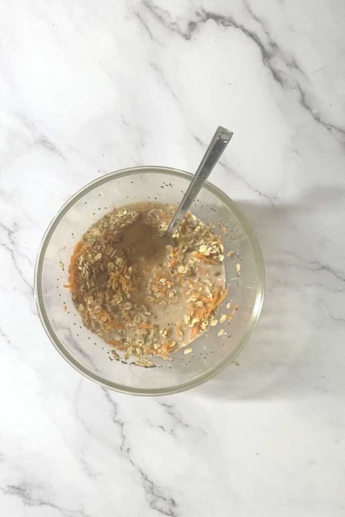 Oats, chia seeds, sweetener, carrots and walnuts in a bowl mixed together.
