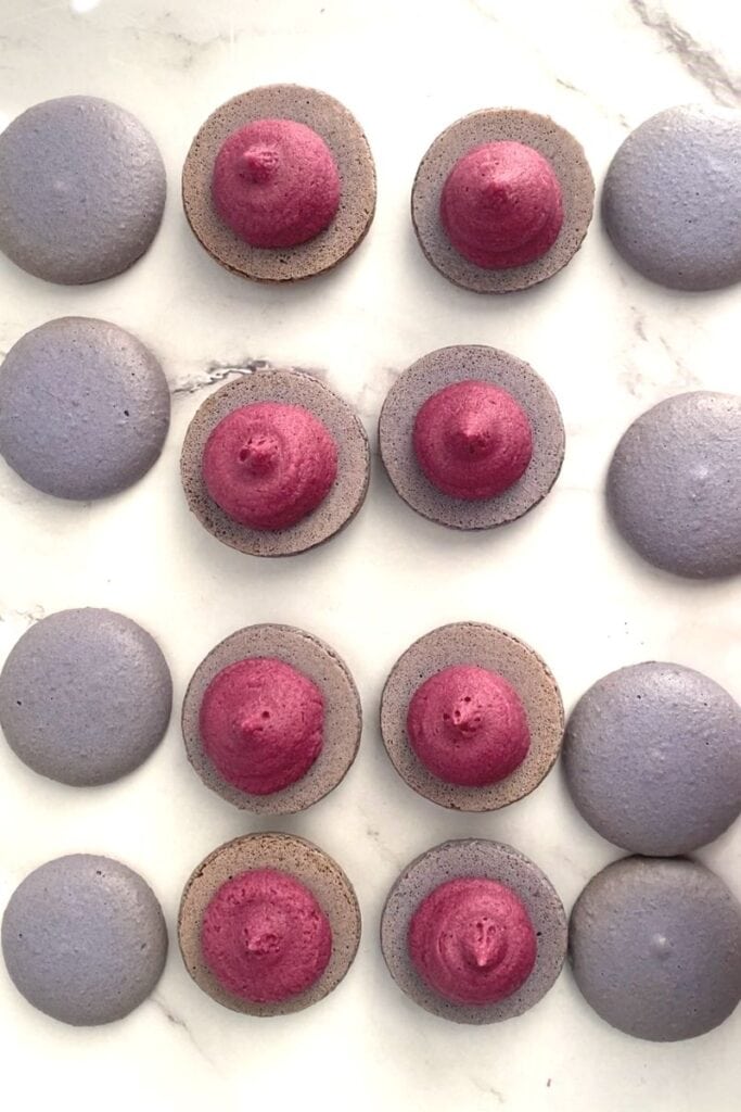 Blueberry buttercream piped into macarons.