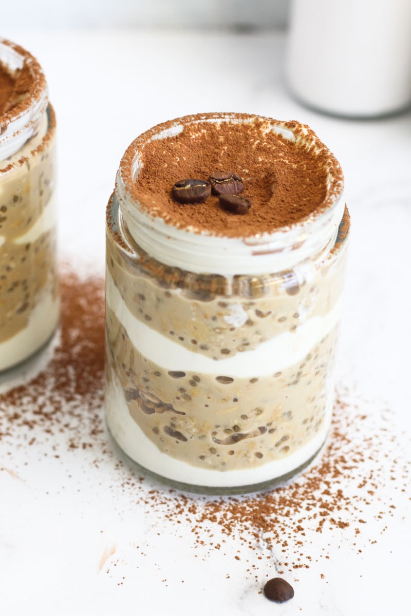 Close up of jar of Tiramisu overnight oats topped with cocoa powder and coffee beans.