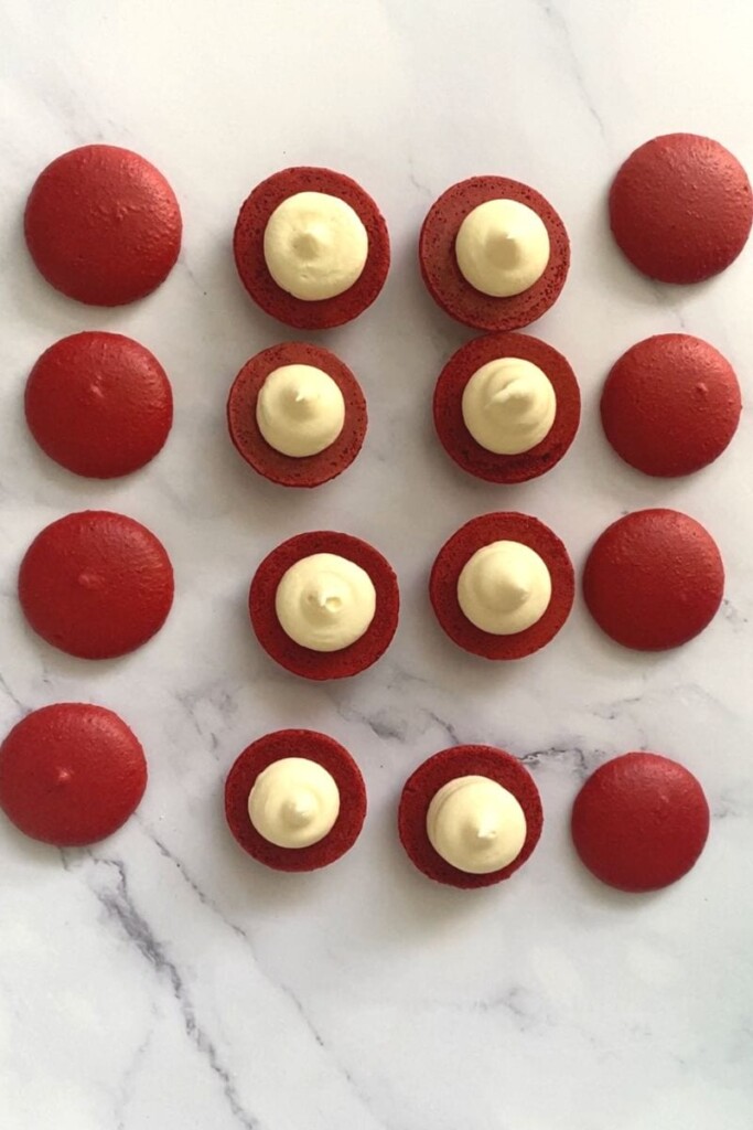 Red velvet macaron shells piped with cream cheese buttercream.