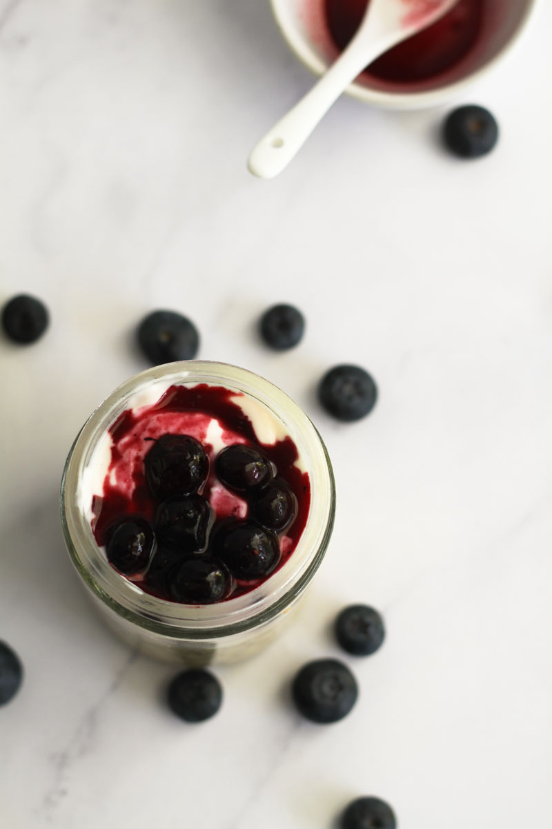 Top view of blueberry cheesecake overnight oats topped with frozen blueberries.