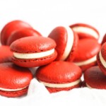 Red velvet macarons laid next to and stacked on one another.
