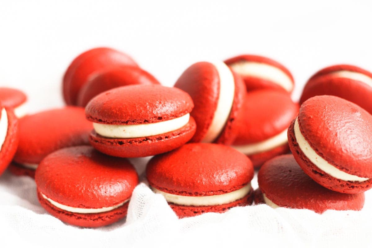 Red velvet macarons laid next to and stacked on one another.