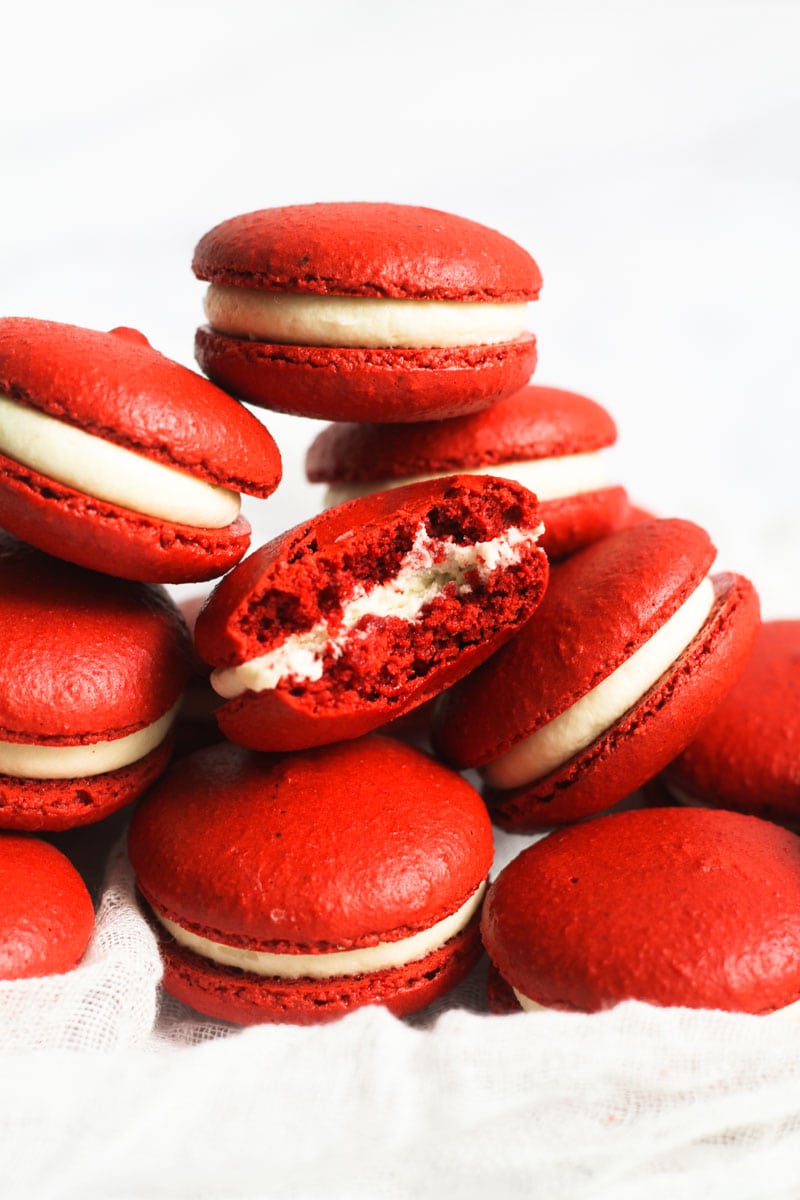 Red velvet macarons filled and stacked with the top macaron with a bite out of it.