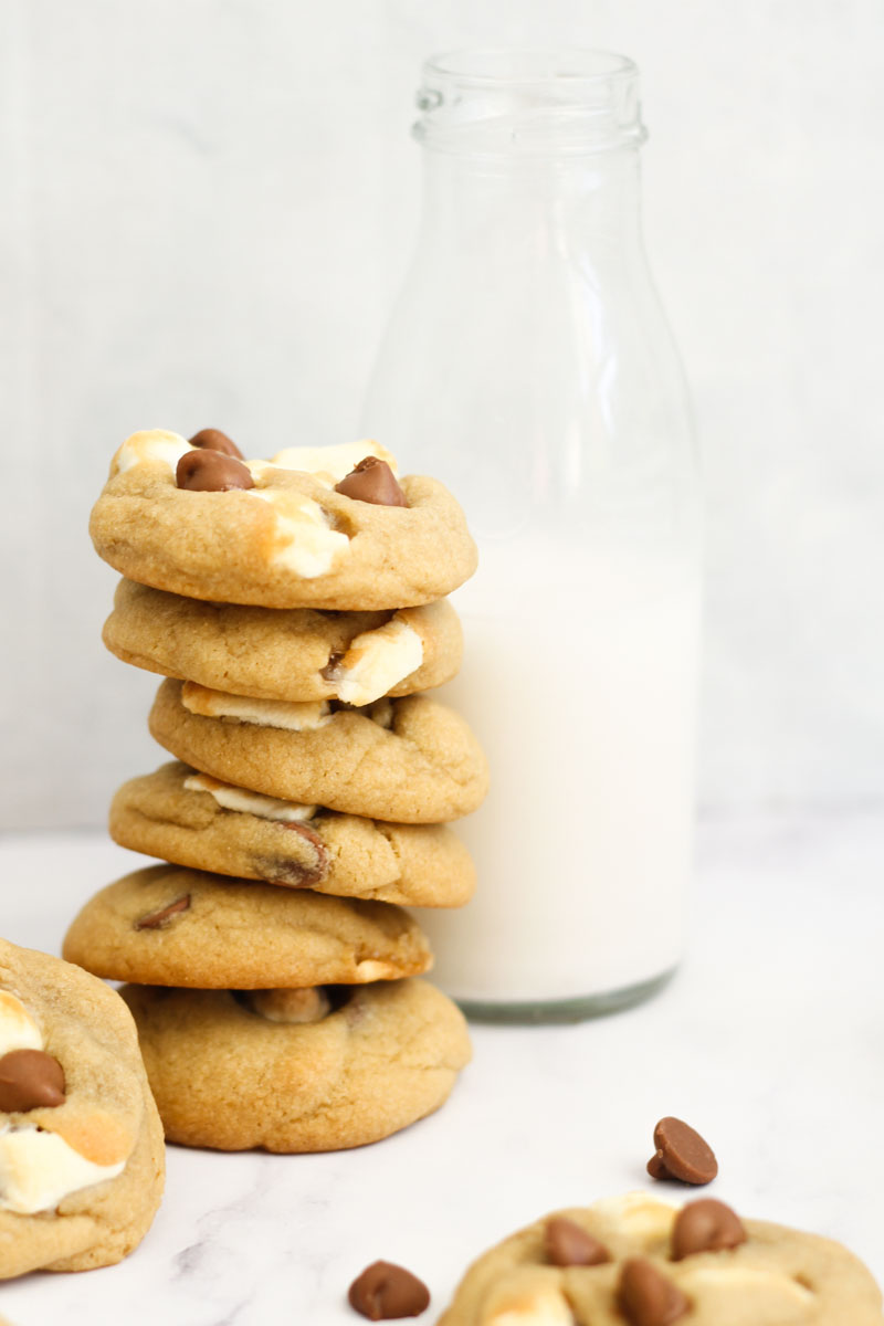 Chocolate chip marshmallow cookies stacked against milk jug.