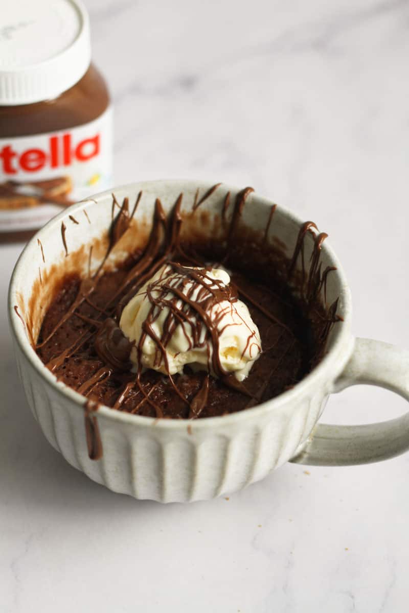 Mug cake nutella flavored topped with ice cream.