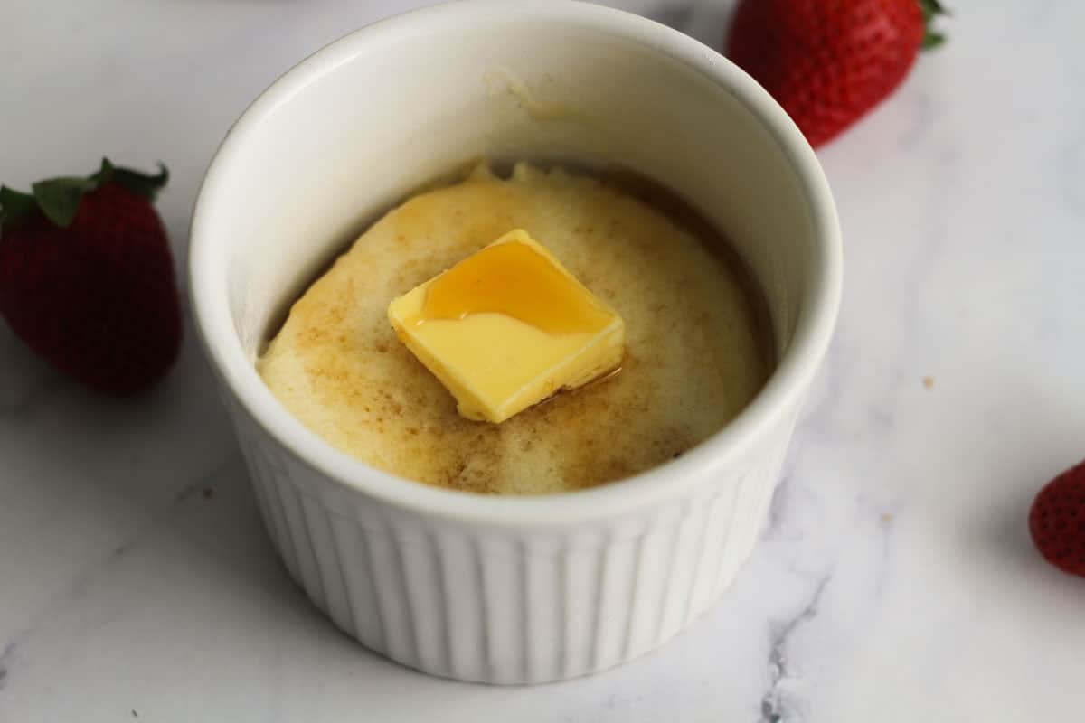 Mug pancake with maple syrup and square of butter.