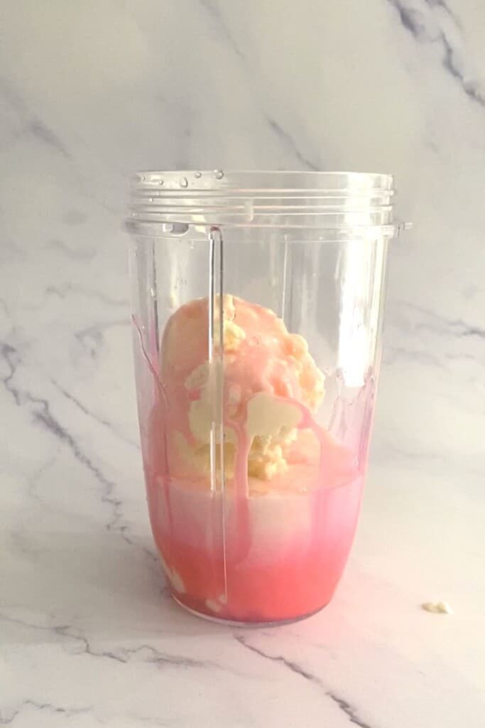 Ice cream, milk and rose syrup in blender.