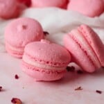 Rose Macarons next to each other along with some rose petals.