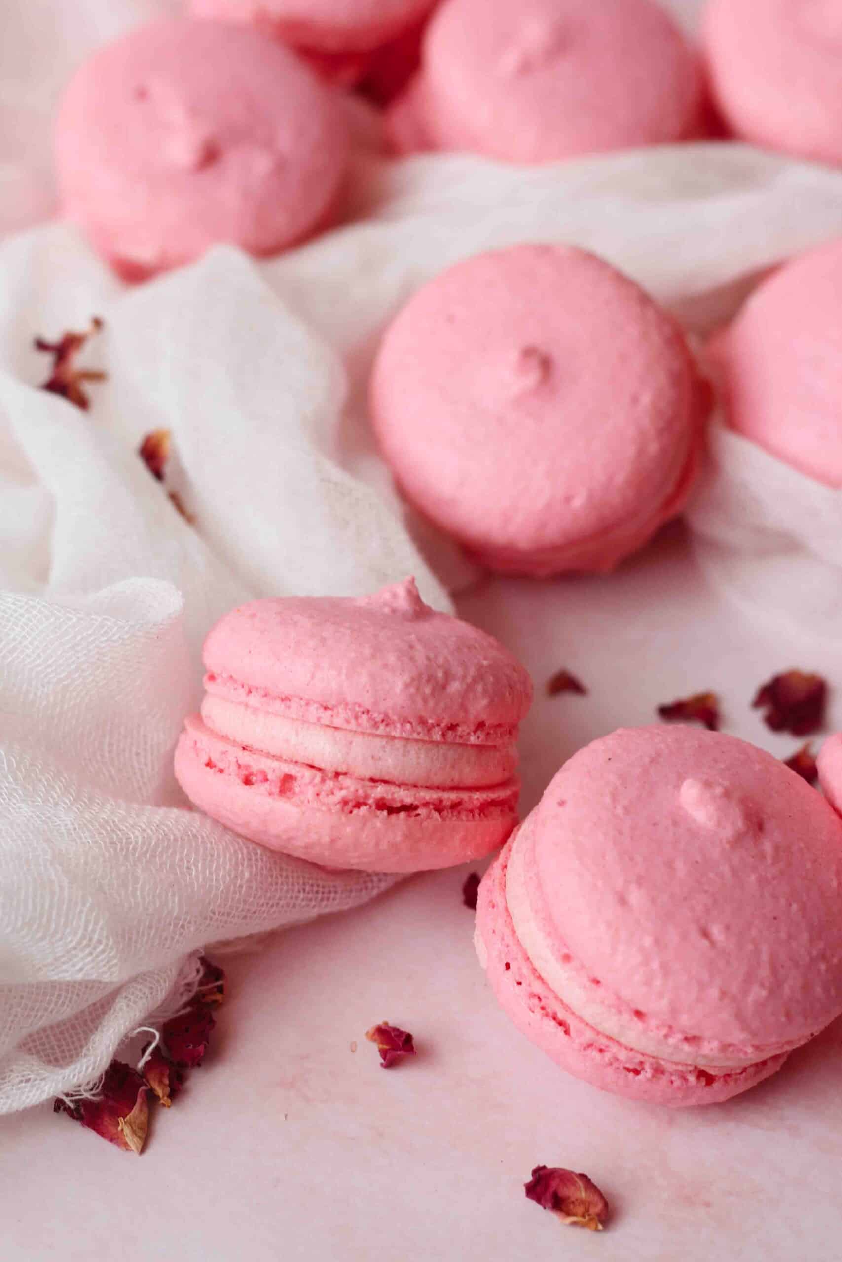 Close up of Rose Macarons on cheese cloth decorated with rose petals.