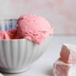 Scoop of pink ice cream flavored with turkish delight and dripping out of a small bowl.