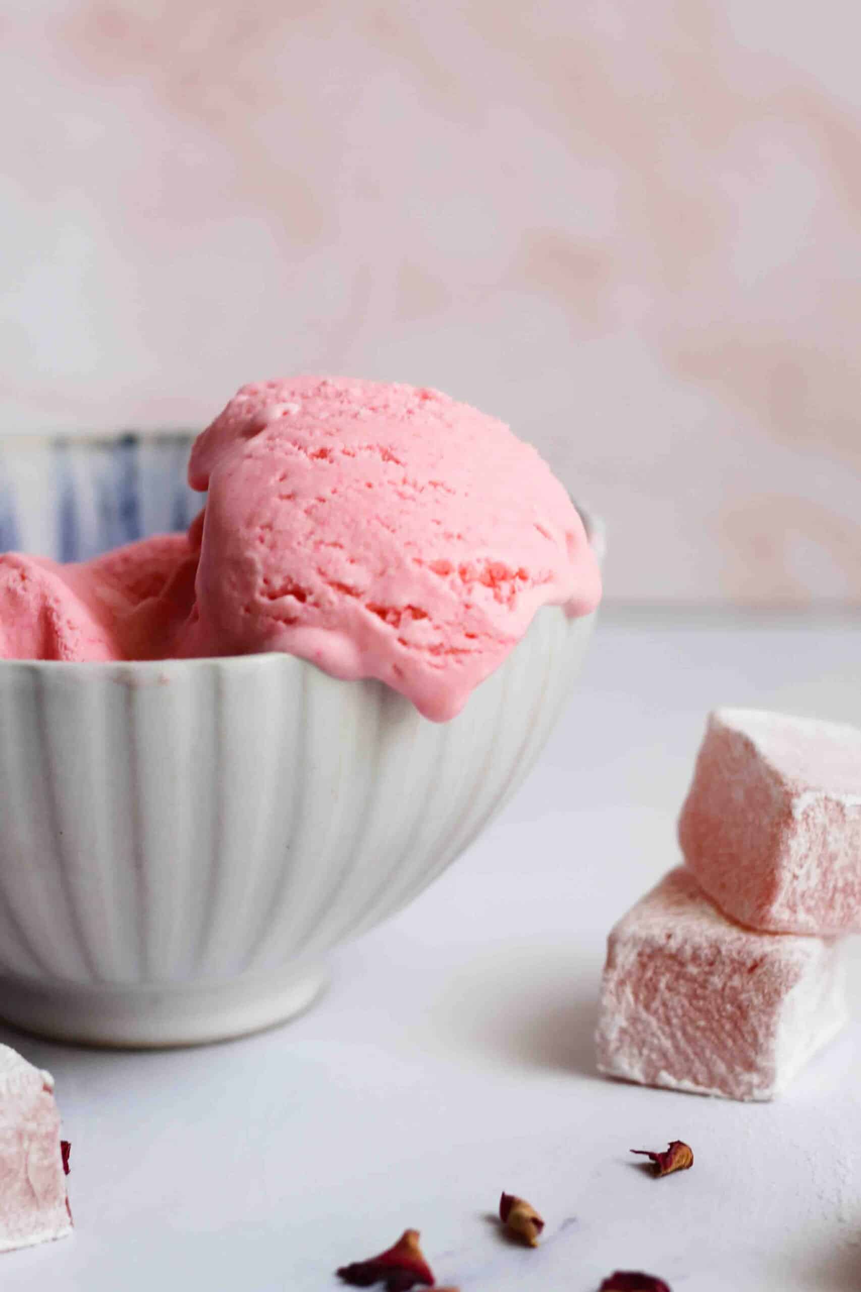 Scoop of pink ice cream flavored with turkish delight and dripping out of a small bowl.