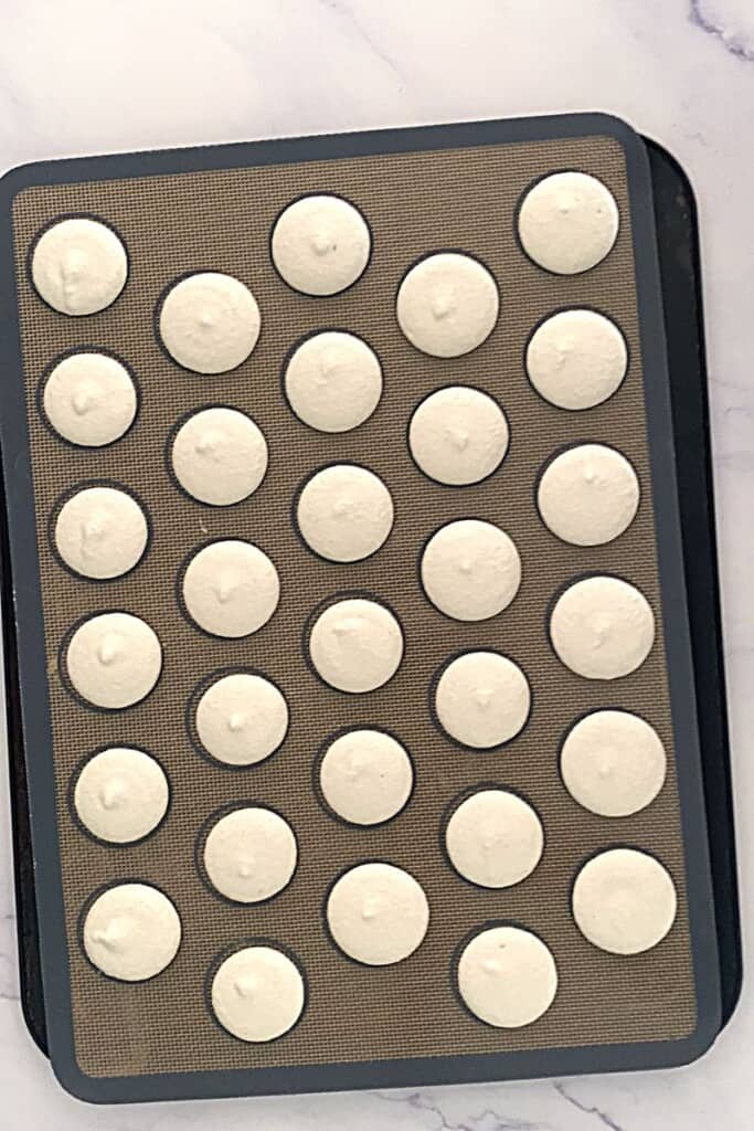 White macaron shells piped onto tray.
