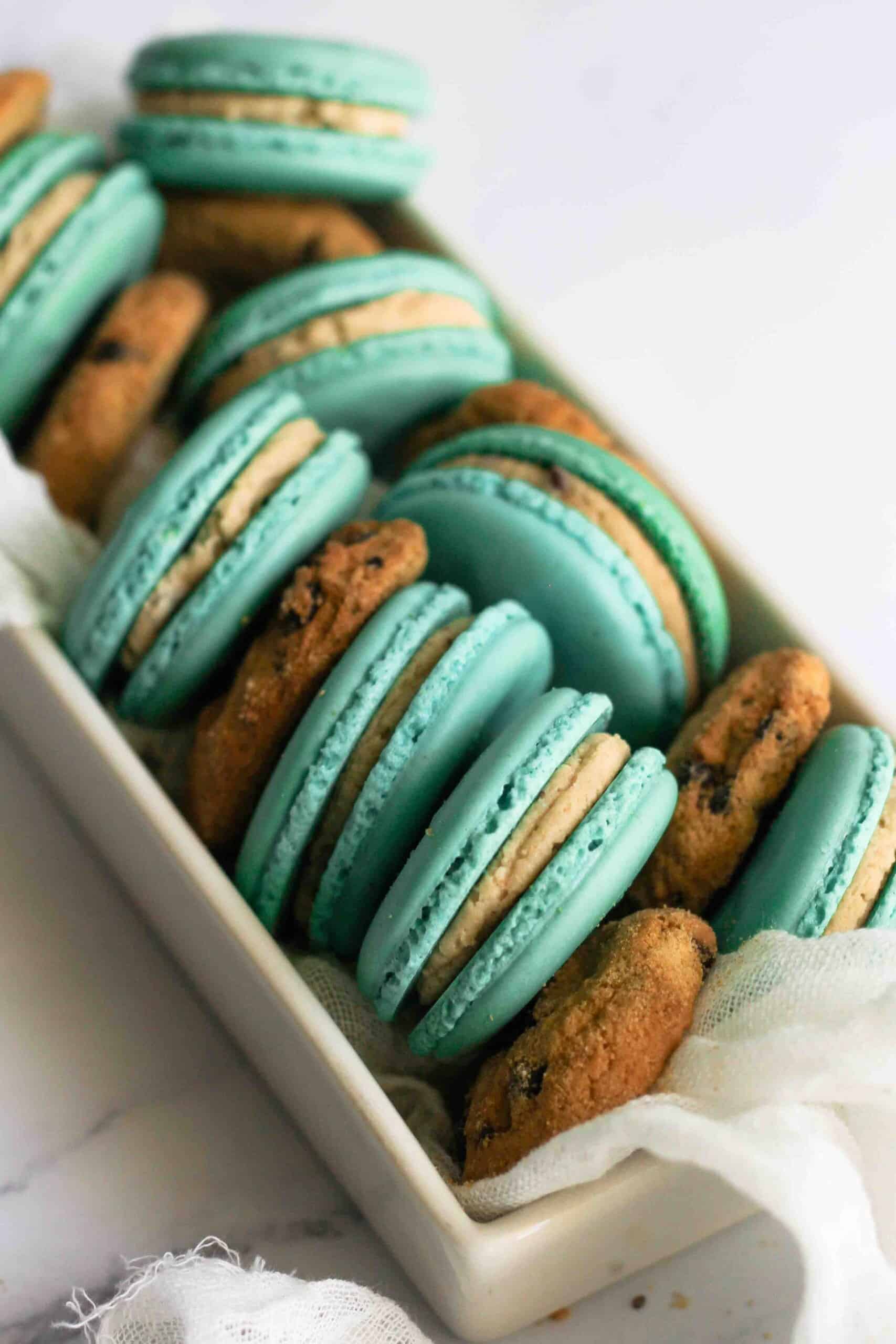 Blue macarons with cookie dough filling a bowl with cookies.